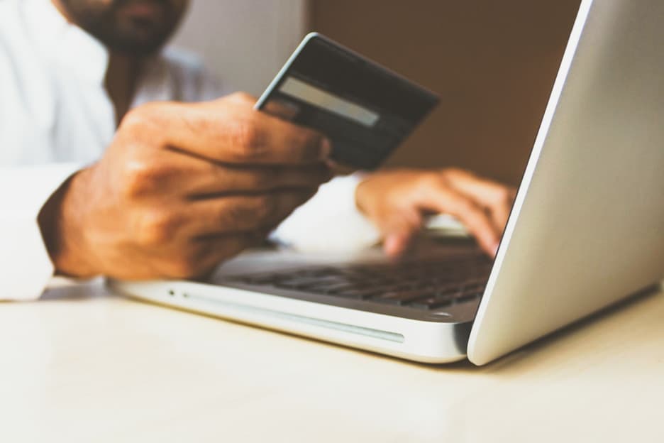 Hand entering a card number on a laptop